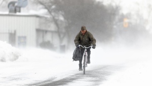 A man rides his bike down the street in Fort Erie, Ont., during an early winter storm that delivered high winds and large amounts of snow across southern Ontario and western New York, Saturday, Nov. 19, 2022. Canadians enjoying a brief relief from the onset of winter-like conditions may want to enjoy the temperatures while they can because The Weather Network is forecasting a colder than normal start to winter across most of the country. THE CANADIAN PRESS/Nick Iwanyshyn