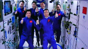 In this photo released by Xinhua News Agency, an image captured off a screen at the Jiuquan Satellite Launch Center in northwest China shows the Shenzhou-15 and Shenzhou-14 crew taking a group picture with their thumbs up after a historic gathering in space on Wednesday, Nov. 30, 2022. Three Chinese astronauts docked early Wednesday with their country's space station, where they will overlap for several days with the three-member crew already onboard and expand the facility to its maximum size. (Guo Zhongzheng/Xinhua via AP)
