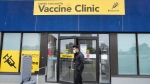 A staff member at a vaccine clinic looks outside the clinic for people waiting to get their COVID-19 vaccine or flu shot during the COVID-19 pandemic, in Mississauga, Ont., on Wednesday, April 13, 2022. THE CANADIAN PRESS/Nathan Denette 
