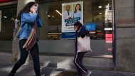 Pedestrians walk by a sign in a store window encouraging people to receive a seasonal flu shot in Toronto on Tuesday, October 19, 2021. THE CANADIAN PRESS/Evan Buhler 