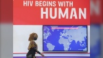 A woman walks by a sign during the AIDS 2022 conference in Montreal, Sunday, July 31, 2022. HIV activists are marking World AIDS Day by urging Ottawa to help stop a global backslide in progress on stemming infections and stigma. THE CANADIAN PRESS/Graham Hughes