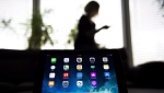A woman uses her smartphone as apps are shown on an iPad in Mississauga, Ont., Monday, Nov. 13, 2017. A new report shows women, people of colour and immigrants in Canada's tech sector saw employment and pay inequities persist -- and in some cases, worsen -- between 2001 and 2016. THE CANADIAN PRESS/Nathan Denette