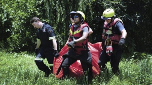 Rescuers carry the body of a flood victim that was retrieved from the Jukskei river in Johannesburg, Sunday, Dec. 4, 2022. At least nine people have died while eight others are still missing in South Africa after they were swept away by a flash flood along the Jukskei river in Johannesburg, rescue officials said Sunday. (AP Photo)
