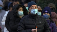 A man wearing a face mask holds his testing tube as masked residents line up for their routine COVID-19 throat swabs at a coronavirus testing site in Beijing, Sunday, Dec. 4, 2022. China on Sunday reported two additional deaths from COVID-19 as some cities move cautiously to ease anti-pandemic restrictions amid increasingly vocal public frustration over the measures. (AP Photo/Andy Wong)
