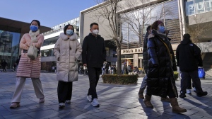 People wearing face masks walk through a reopened open air shopping mall in Beijing, Sunday, Dec. 4, 2022. China on Sunday reported two additional deaths from COVID-19 as some cities move cautiously to ease anti-pandemic restrictions amid increasingly vocal public frustration over the measures. (AP Photo/Andy Wong)