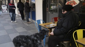 Levent Yurdadogan, 34, shares his pizza with his 11-year-old dog Sansli (Lucky) at a restaurant in Ankara, Turkey, Monday, Dec. 5, 2022. Annual inflation in Turkey slightly eased in November for the first time in more than a year, according to official figures released on Monday, although it remains close to 24-year highs. (AP Photo/Burhan Ozbilici)