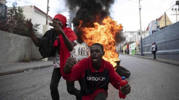 Protesters sing an anti-government song in front of a barricade of burning tires during a protest against the government in Port-au-Prince, Haiti, Friday, Nov. 18, 2022. (AP Photo/Odelyn Joseph)