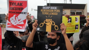 Activists hold up posters during a rally against Indonesia's new criminal law in Yogyakarta, Indonesia, Tuesday, Dec. 6, 2022. The country's parliament passed the long-awaited and controversial revision of its penal code Tuesday that criminalizes extramarital sex for citizens and visiting foreigners alike. Writings on the posters read "Reject the revised penal code" and "Revised criminal law shackles press freedom." (AP Photo/Slamet Riyadi)