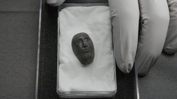 Liz Barham, senior conservator of the Museum of London Archaeology, displays an early medieval silver head with blue glass eyes during a photo call, in London, Tuesday, Dec. 6, 2022. A silver head found during construction of a housing development marks the grave of a powerful woman who may have been an Anglo-Saxon aristocrat or early Christian religious leader in Britain. (AP Photo/Kin Cheung)