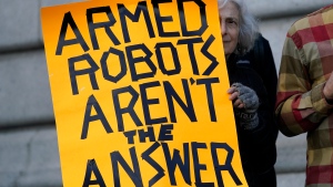 Diana Scott holds up a sign while taking part in a demonstration about the use of robots by the San Francisco Police Department outside of City Hall in San Francisco, Monday, Dec. 5, 2022. The unabashedly liberal city of San Francisco became the unlikely proponent of weaponized police robots this week after supervisors approved limited use of the remote-controlled devices, addressing head-on an evolving technology that has become more widely available even if it is rarely deployed to confront suspects. (AP Photo/Jeff Chiu)