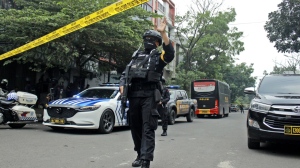 A police officer gestures at the crowd to move back as he guards a road leading to a police station where a bomb exploded in Bandung, West Java, Indonesia, Wednesday, Dec. 7, 2022. A man blew himself up Wednesday at a police station on Indonesia's main island of Java in what appeared to be the latest in a string of suicide attacks in the world's most populous Muslim nation. (AP Photo/Kholid Parmawinata)