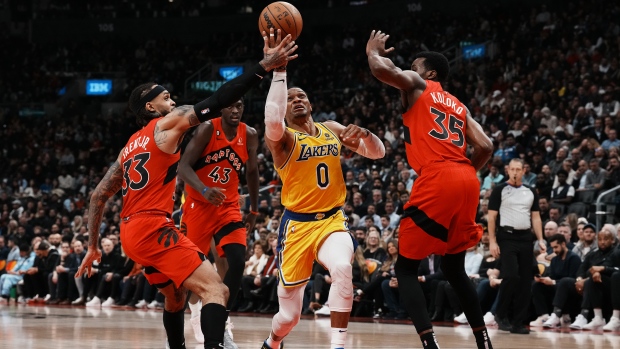 Los Angeles Lakers' Russell Westbrook drives between Toronto Raptors' Gary Trent Jr. (left) and Christian Koloko during first half NBA basketball action in Toronto on Wednesday, December 7, 2022. THE CANADIAN PRESS/Chris Young