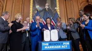 House Speaker Nancy Pelosi of Calif., accompanied by Senate Majority Leader Sen. Chuck Schumer of N.Y., center left, and other members of congress, signs the H.R. 8404, the Respect For Marriage Act, on Capitol Hill in Washington, Thursday, Dec. 8, 2022. (AP Photo/Andrew Harnik)