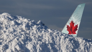 The tail of an Air Canada aircraft is seen behind a pile of snow at Vancouver International Airport in Richmond, B.C., Wednesday, Dec. 21, 2022. The airport is limiting international flights to carriers registered in Canada and the U.S. for two days as it attempts to clear a backlog of aircraft and passengers after a snowstorm caused massive disruptions this week. THE CANADIAN PRESS/Darryl Dyck