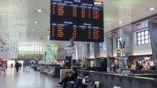 People sit near a Via Rail schedule board