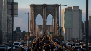 People walk on the Brooklyn Bridge at sunset, Friday, Nov. 18, 2022, in New York. (AP Photo/Julia Nikhinson)