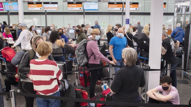 FILE - Travellers wait in line at a Sunwing Airlines check-in desk at Trudeau Airport in Montreal, Wednesday, April 20, 2022. THE CANADIAN PRESS/Graham Hughes