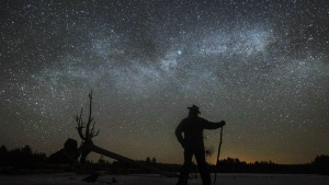 FILE - Dave Cooke observes the Milky Way over a frozen fish sanctuary in central Ontario, north of Highway 36 in Kawartha Lakes, Ontario, Canada, early Sunday, March 21, 2021. According to research published in the journal Science on Thursday, Jan. 19, 2023, every year the night sky grows brighter, and the stars look dimmer. Analyzing data from more than 50,000 citizen scientists, or amateur stargazers, reveals that artificial lighting is making the night sky about 10% brighter each year, a faster rate of change that scientists had previously estimated looking at satellite data. (Fred Thornhill/The Canadian Press via AP)