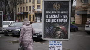 A woman walks past a banner reading "Marines - Heroes of Mariupol - Do not forget those who are still in captivity", in Kryvyi Rih, Ukraine, Sunday, Jan. 29, 2023. (AP Photo/Daniel Cole)