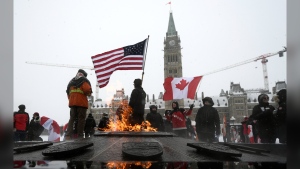 Demonstrators hold flags as they mark the one-year anniversary of the Freedom Convoy on Parliament Hill in Ottawa, on Sunday, Jan. 29, 2023. THE CANADIAN PRESS/Justin Tang