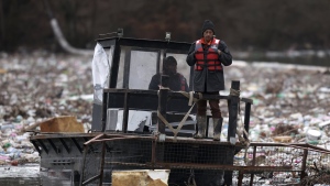 Utility company workers push the waste to the shore of Lim river near Priboj, Serbia, Monday, Jan. 30, 2023. Plastic bottles, wooden planks, rusty barrels and other garbage dumped in poorly regulated riverside landfills or directly into the rivers accumulated during high water season, behind a trash barrier in the Lim river in southwestern Serbia. (AP Photo/Armin Durgut)