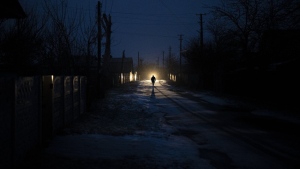 A man is silhouetted in the headlights of a car during a blackout in the town of Kolychivka, Ukraine, Wednesday, Feb. 1, 2023. (AP Photo/Daniel Cole)