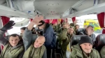 In this handout photo taken from video released by Russian Defense Ministry Press Service on Saturday, Feb. 4, 2023, a group of Russian soldiers wave at a cameraman sitting in a bus after being released in a prisoners swap between Russia and Ukraine somewhere at an unspecified location in Belgorod region in Russia.(Russian Defense Ministry Press Service via AP)