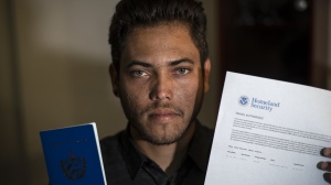 Marcos Marzo poses with his passport and his permit to travel to the United States, at his home in Havana, Cuba, Wednesday, Jan. 25, 2023. A close relative told Marzo on Jan. 21 that he had applied online to sponsor his trip to Florida as required bythe new parole program for Cuban migrantsset up by the Biden administration. The next day the sponsorship had been confirmed and the day after that it was approved. (AP Photo/Ramon Espinosa)