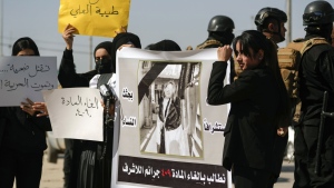 Demonstrators hold placards and a poster with a picture of Tiba Ali, a YouTube star who was recently killed by her father, in Diwaniya, Iraq, Sunday, Feb. 5, 2023. Iraq's Interior Ministry spokesman Saad Maan on Friday announced that Tiba Ali was killed by her father on Jan. 31, who then turned himself into the police. (AP Photo/Hadi Mizban)