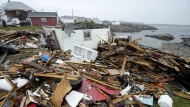 A resident and search and rescue worker examine the destroyed remains of a home in Port aux Basques, N.L., Monday, Sept.26, 2022. Three tupperware bins hold all that remains of Peggy Savery's life and home since post-tropical storm Fiona ravaged her Newfoundland community and swept away most of her possessions last September. THE CANADIAN PRESS/Frank Gunn