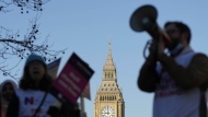 A protestor with a megaphone shouts slogans in front of Big Ben as nurses of the nearby St. Thomas' Hospital protest in London, Monday, Feb. 6, 2023. Tens of thousands of nurses and ambulance staff are walking off the job in the U.K. in what unions called the biggest strike in the history of the country's public health system. (AP Photo/Frank Augstein)