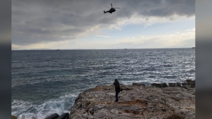 In this photo provided by the Greek Coast Guard, a helicopter searches over the Aegean Sea near the northwestern island of Lesbos, Greece, Tuesday, Feb. 7, 2023. Three migrants died and 16 were rescued off the Greek island of Lesbos Tuesday after a dinghy transporting them from the nearby coast of Turkey hit rocks in high winds, authorities said. (Greek Coast Guard via AP)