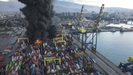 Smoke rises from burning containers at the port in the earthquake-stricken town of Iskenderun, southern Turkey, Tuesday, Feb. 7, 2023. Television images on Tuesday showed thick black smoke rising from burning containers at Iskenderun Port. Reports said the fire was caused by containers that toppled over during the powerful earthquake that struck southeast Turkey on Monday. Turkey's state-run Anadolu Agency said a Turkish Coast Guard vessel was assisting efforts to extinguish fire. (Serdar Ozsoy/Depo Photos via AP)