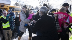 Parents and their children are loaded onto a warming bus as they wait for news after a bus crashed into a daycare centre in Laval, Que., on Wednesday, Feb. 8, 2023. THE CANADIAN PRESS/Ryan Remiorz