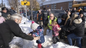Parents and their children are loaded onto a warming bus as they wait for news after a bus crashed into a daycare centre in Laval, Que., Wednesday, Feb. 8, 2023. THE CANADIAN PRESS/Ryan Remiorz