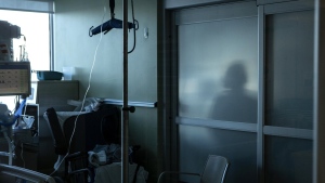 A nurse is silhouetted behind a glass panel as she tends to a patient in the Intensive Care Unit at the Bluewater Health Hospital in Sarnia, Ont., Tuesday, Jan. 25, 2022. THE CANADIAN PRESS/Chris Young
