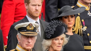 FILE - Britain's King Charles III, from bottom left, Camilla, the Queen Consort, Prince Harry and Meghan, Duchess of Sussex watch as the coffin of Queen Elizabeth II is placed into the hearse following the state funeral service in Westminster Abbey in central London Monday Sept. 19, 2022. (AP Photo/Martin Meissner, Pool) 