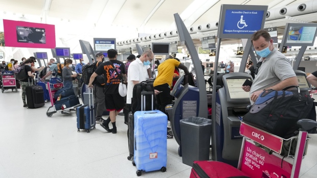 People wait in line to check in at Pearson International Airport in Toronto on Thursday, May 12, 2022. Canadian travellers are facing increased airport fees after the pandemic grounded revenues and led to accumulating debt for airports across the country. THE CANADIAN PRESS/Nathan Denette