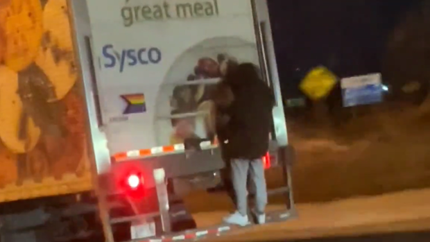 El hombre colgado de la parte trasera de un camión de transporte en el QEW