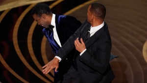 Will Smith, right, hits presenter Chris Rock on stage while presenting the award for best documentary feature at the Oscars on Sunday, March 27, 2022, at the Dolby Theatre in Los Angeles. (AP Photo/Chris Pizzello) 