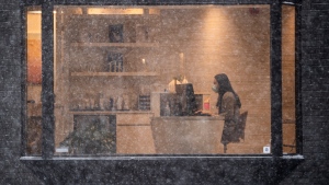 A person works inside a business as snow falls outside in Ottawa, on Monday, Jan. 17, 2022. THE CANADIAN PRESS/Justin Tang