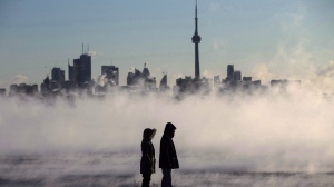 Steam rises as people look out on Lake Ontario in front of the skyline during extreme cold weather in Toronto on Saturday, February 13, 2016. THE CANADIAN PRESS/Mark Blinch