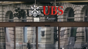 A woman walks past the entrance of the headquarters of the Swiss banks Credit Suisse and UBS at the Paradeplatz in Zurich, Switzerland, Sunday March 19, 2023. (Michael Buholzer/Keystone via AP)