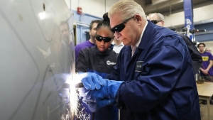 Ontario Premier Doug Ford, right, gets help from grade 11 student Shannon Williams, 16, as they practise plasma welding on a car hood while visiting St. Mary Catholic Secondary School in Pickering, Ont., on Wednesday, March 8, 2023. THE CANADIAN PRESS/Nathan Denette