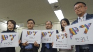 LGBTQ activists hold up cards showing a logo each of their newly founded a civil engagement group Pride7, or P7, for the upcoming Group of Seven Summit that Japan hosts in May, to make policy proposals, including a demand that Japan enact anti-discrimination law to guarantee equal rights for them, at a news conference at the Ministry of Health, Labor and Welfare in Tokyo Wednesday, March 22, 2023.(AP Photo/Mari Yamaguchi)
