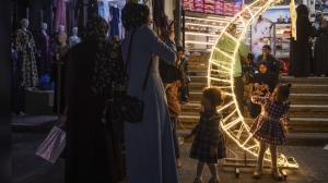 A Palestinian woman takes photos of her daughter next to a crescent moon-shaped decoration in a market, at the beginning of the Muslim holy month of Ramadan in Jebaliya refugee camp, northern Gaza Strip, Wednesday, March 22, 2023. (AP Photo/Fatima Shbair)