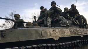 Ukrainian soldiers ride atop an APC on the frontline in Bakhmut, Donetsk region, Ukraine, Wednesday, March 22, 2023. (AP Photo/Libkos)