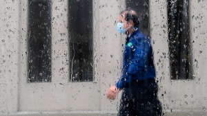 FILE - A pedestrian walks alongside businesses on a rainy day while wearing a protective mask during the COVID-19 pandemic in Toronto on Friday, June 18, 2021.THE CANADIAN PRESS/Nathan Denette 