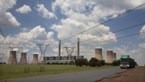 A coal truck, right, passes the coal-powered Duvha power station, near Emalahleni (formerly Witbank) east of Johannesburg, on Nov. 17, 2022. The electricity shortages that plague many of Africa's 54 countries are a serious drain on the continent's economic growth. In recent years South Africa's power generation has become so inadequate that the continent's most developed economy must cope with rolling power blackouts of eight to 10 hours per day. (AP Photo/Denis Farrell, File)