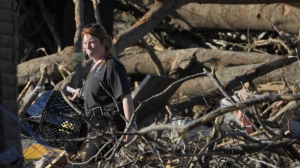 A Rolling Fork, Miss., resident walks through fallen trees as she attempts to salvage personal items following a tornado the night before that heavily damaged the Mississippi Delta community, Saturday, March 25, 2023. (AP Photo/Rogelio V. Solis)